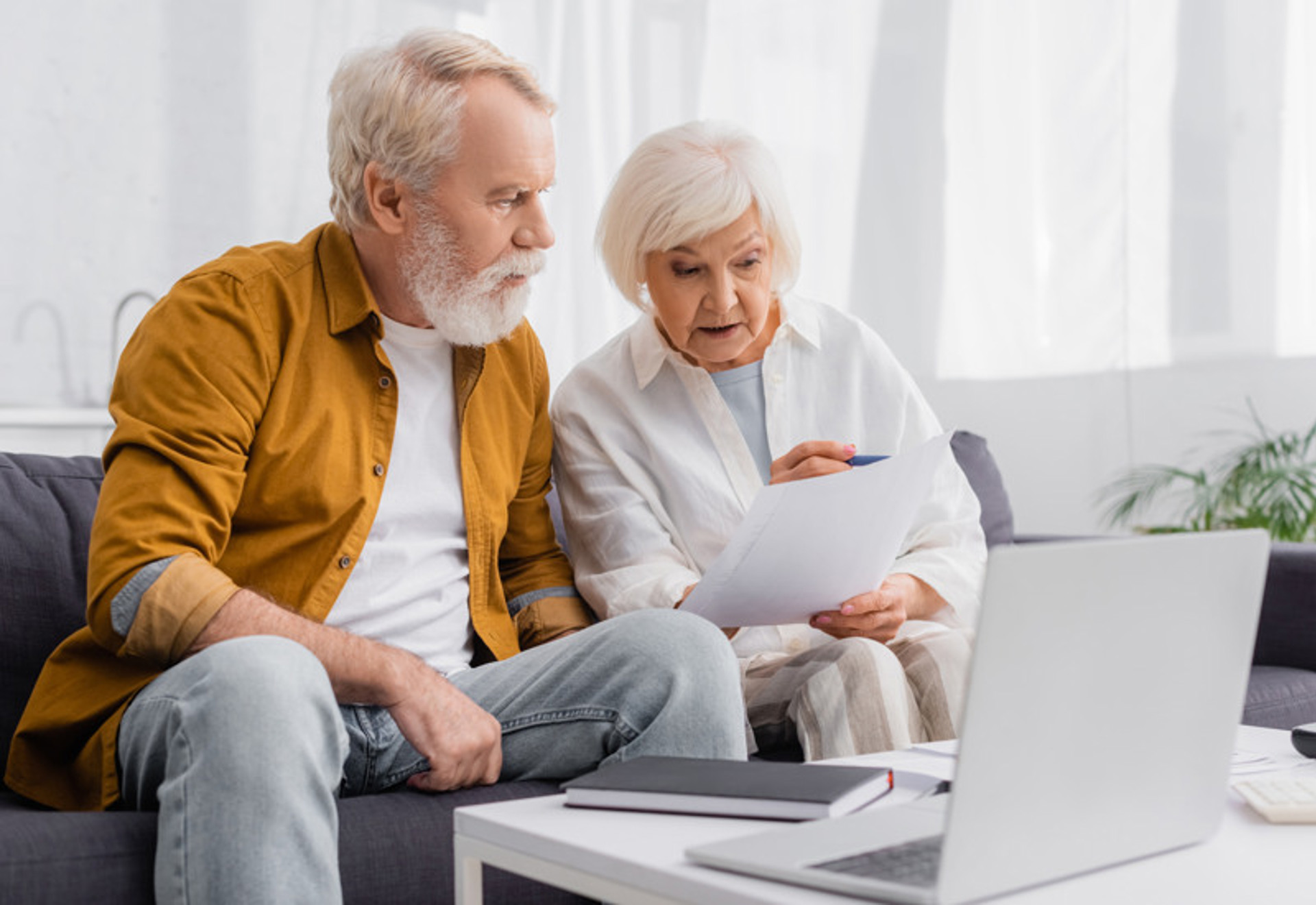 Kontakta hydrostandard - äldre par tittar på papper framför dator